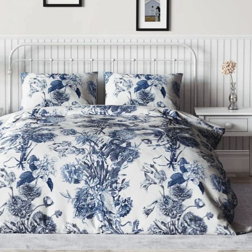Vintage bedroom bedding mockup featuring a white comforter and pillows with a blue floral pattern on a metal bed frame.