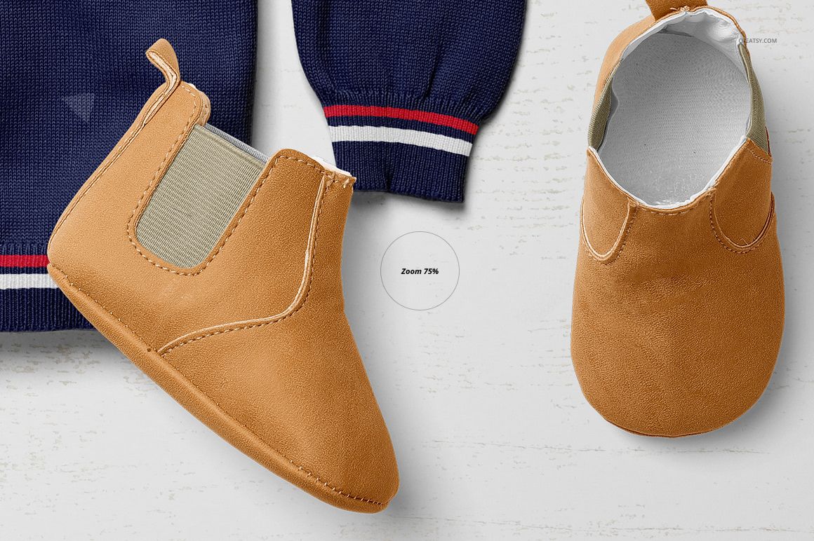 Close-up of a tan baby shoe mockup and navy sweater sleeve with striped cuff, seen from above on a white background.