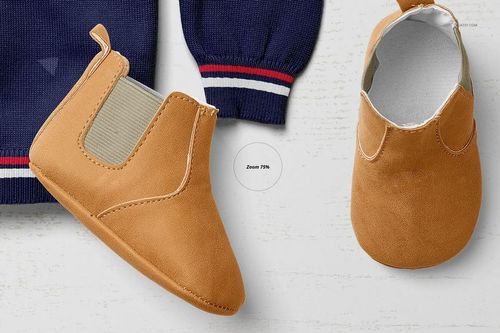 Close-up of a tan baby shoe mockup and navy sweater sleeve with striped cuff, seen from above on a white background.
