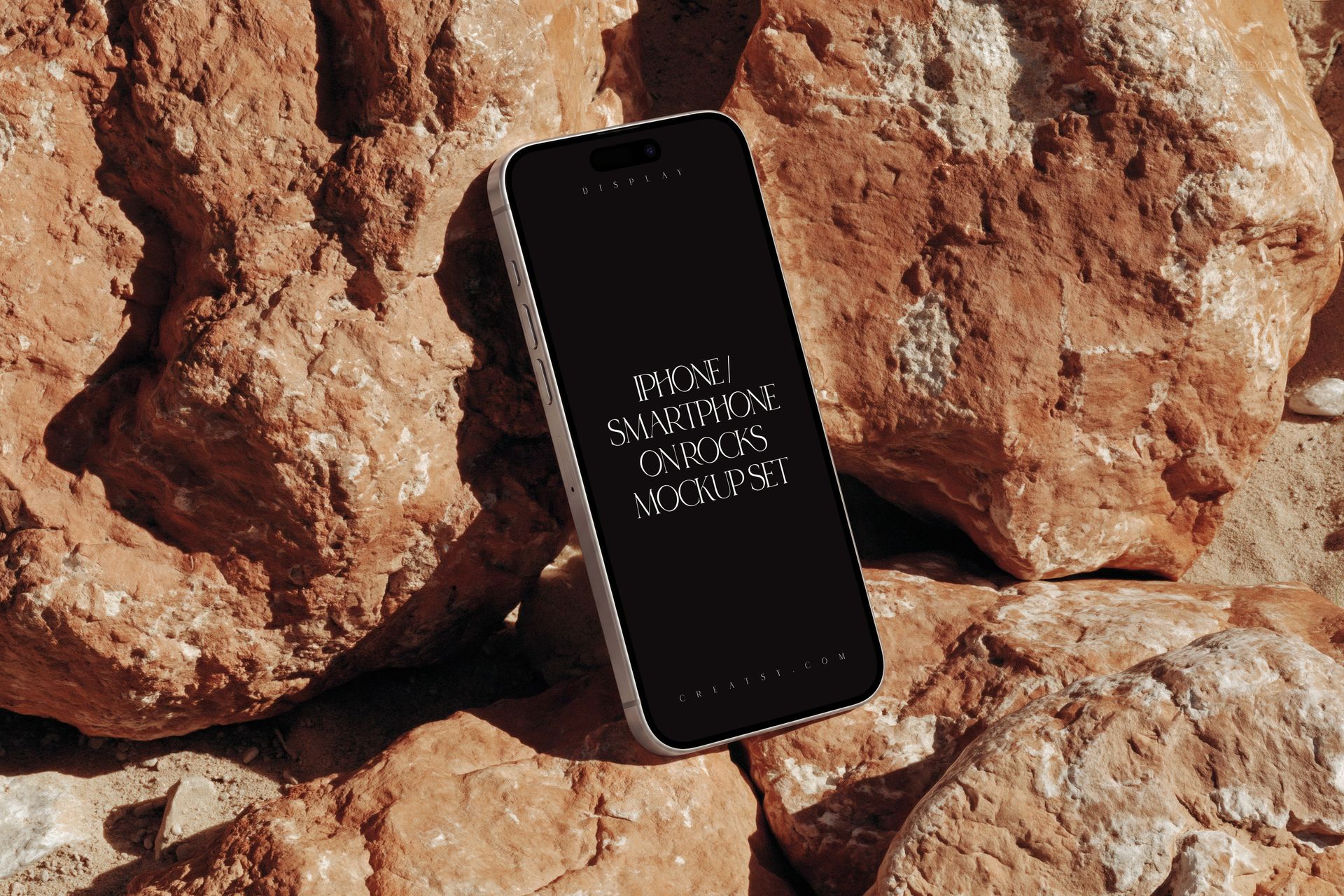 Modern iPhone smartphone with dark screen displayed upright on textured rocks, front view mockup scene.