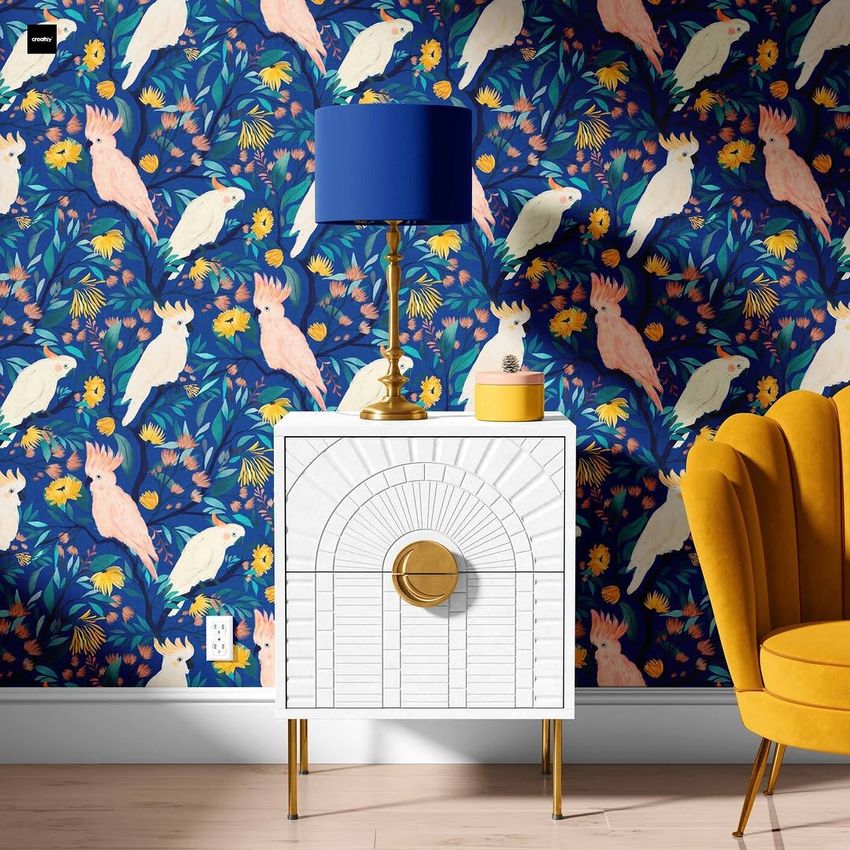 Drum lamp shade mockup featuring a blue lamp on a white cabinet, set against a wallpaper with white parrots and colorful leaves.