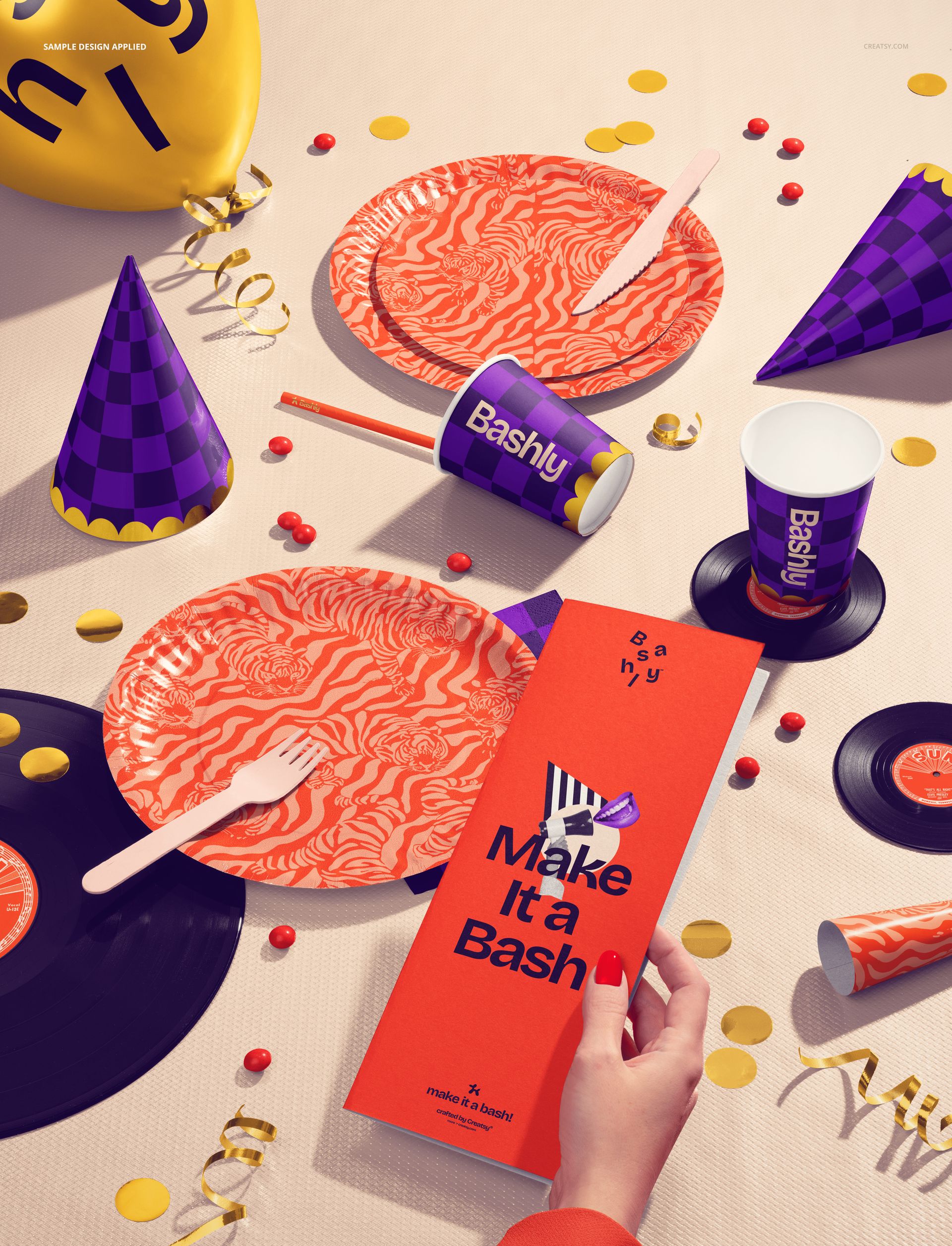 Disposable party tableware mockup featuring orange patterned plates, cups, and hats on a decorated tabletop.