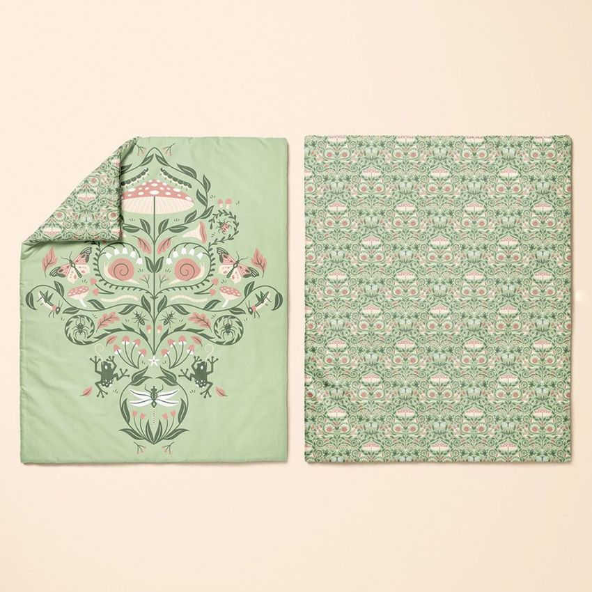 Baby duvet cover mockup featuring two covers laid flat on a beige surface, one with whimsical forest illustrations and one with a repeating owl pattern.
