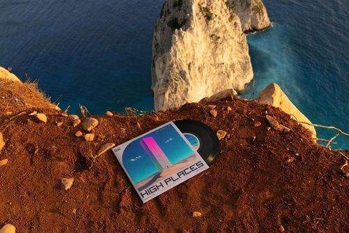 7 inch vinyl record mockup with geometric cover placed on brown rocky ground overlooking sea cliffs and water.