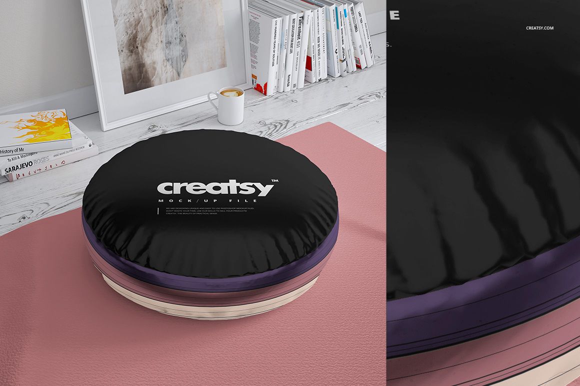 Mockup of two round shiny fabric pillows with black tops and purple sides, displayed on a soft pink rug.