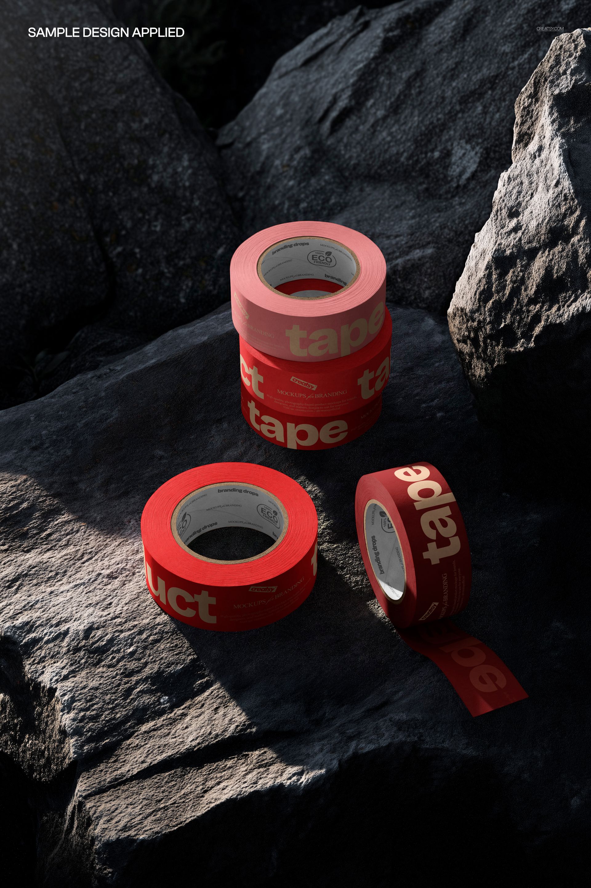 Multiple rolls of red tape with bold white text are arranged on dark natural rocks in a packaging mockup scene.