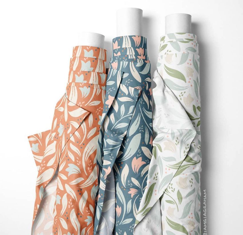Three fabric rolls mockup displayed upright, each featuring a floral leaf pattern in orange, blue, and light green tones.