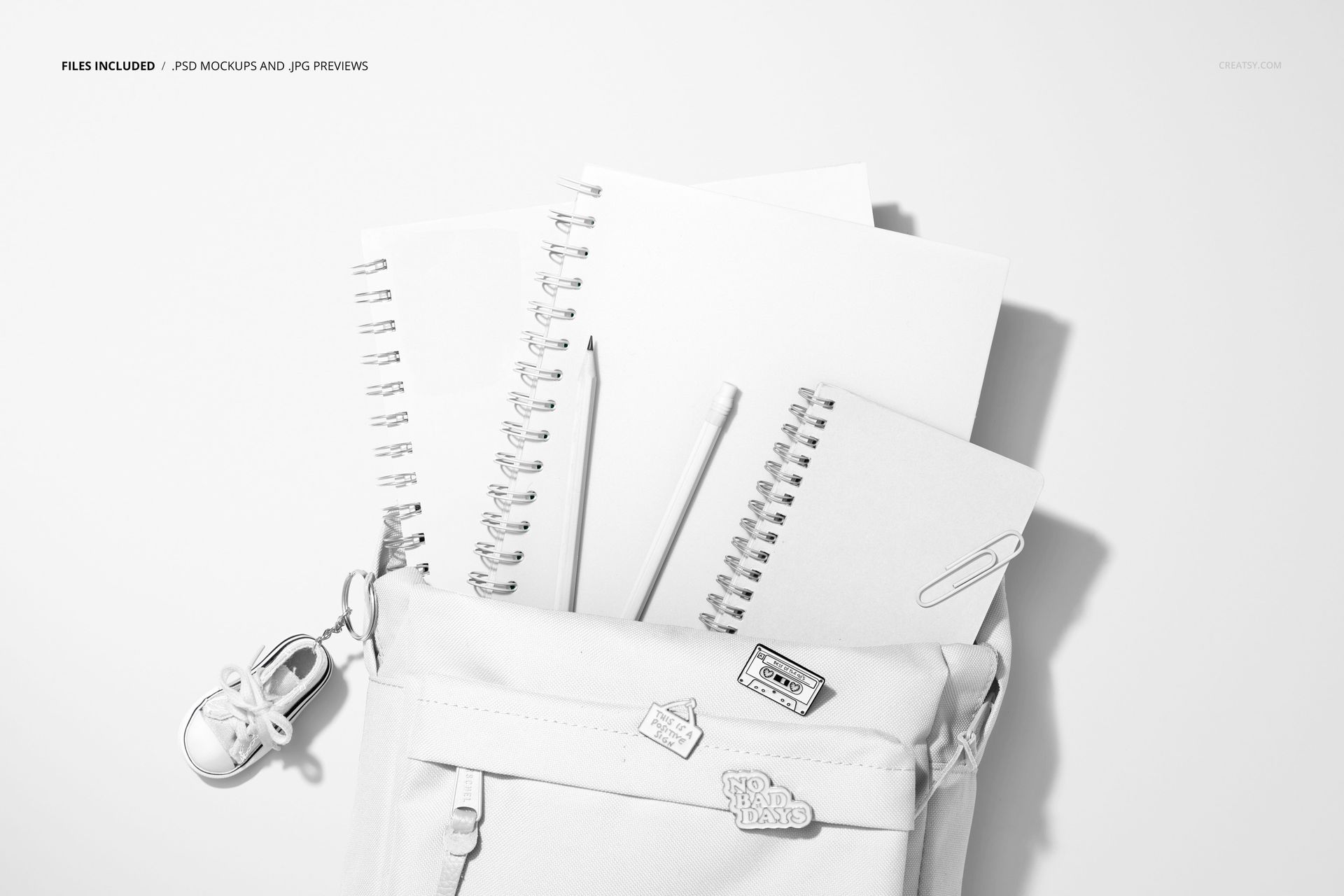 Top-down perspective of a stationery mockup featuring a school backpack, spiral-bound notebooks, and a pen on a white background.