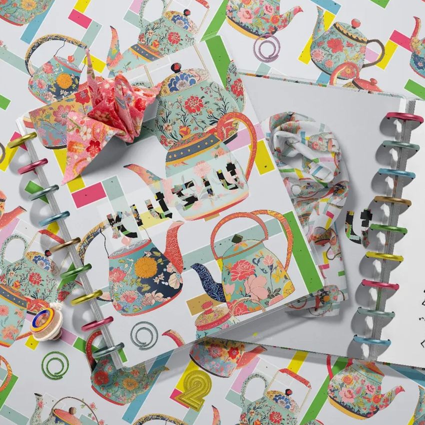 Top view of two spiral planners with colorful teapot illustrations on white covers, surrounded by matching patterned background.