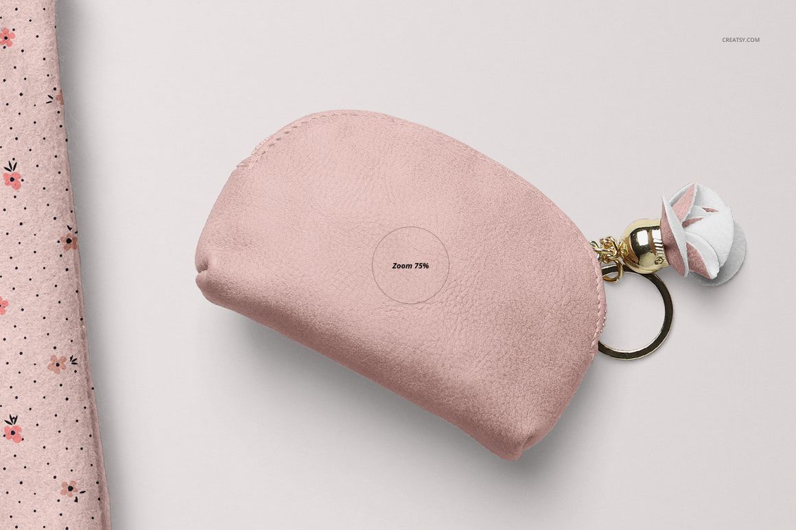 Soft pink zippered pouch mockup with a gold keychain, displayed flat on a pale surface with floral fabric nearby.