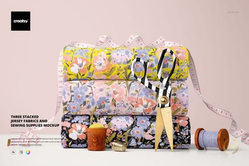 PSD mockup showing three patterned fabric rolls and sewing tools like tape measure, scissors, and spools.