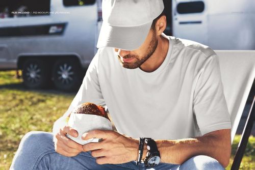 PSD mockup showing a person in casual clothing with a burger, seated outside with a food truck in the background.