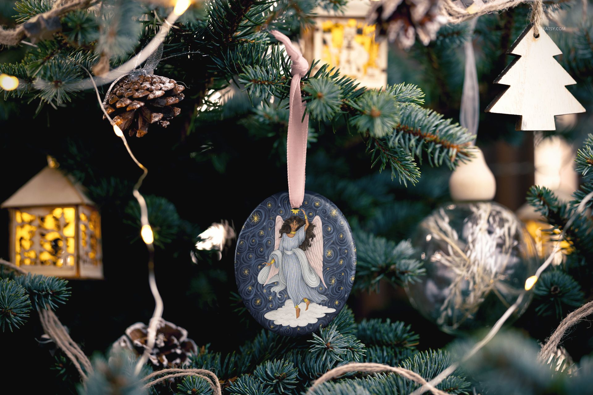 Handmade oval Christmas ornament mockup with painted angel design, displayed on a decorated evergreen branch.