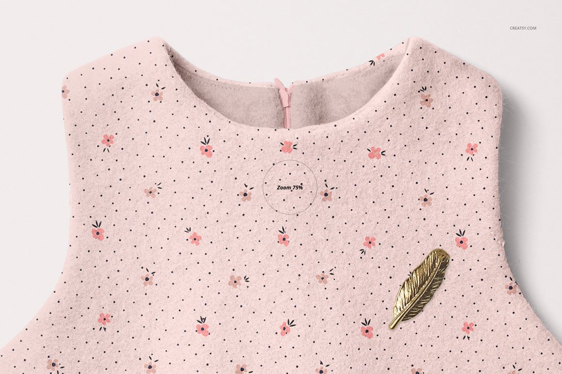 Front view of a baby dress mockup with a soft pink fabric, small floral pattern, and gold feather pin detail.