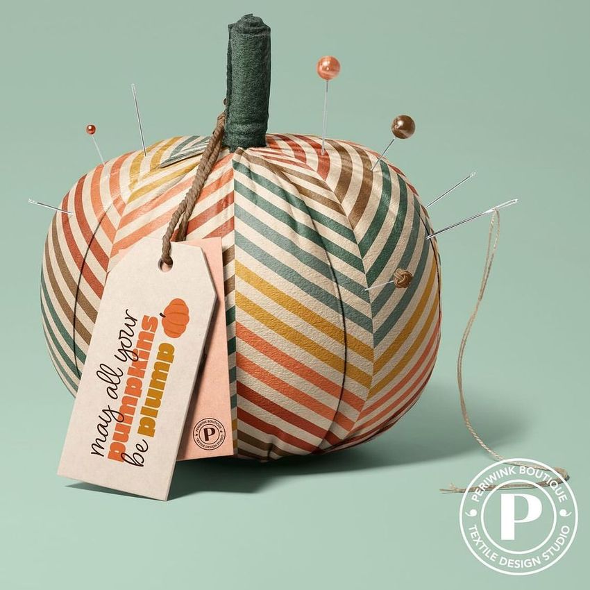 Fabric pumpkin mockup featuring diagonal striped patterns in orange, green, and beige with pins and a tag attached.