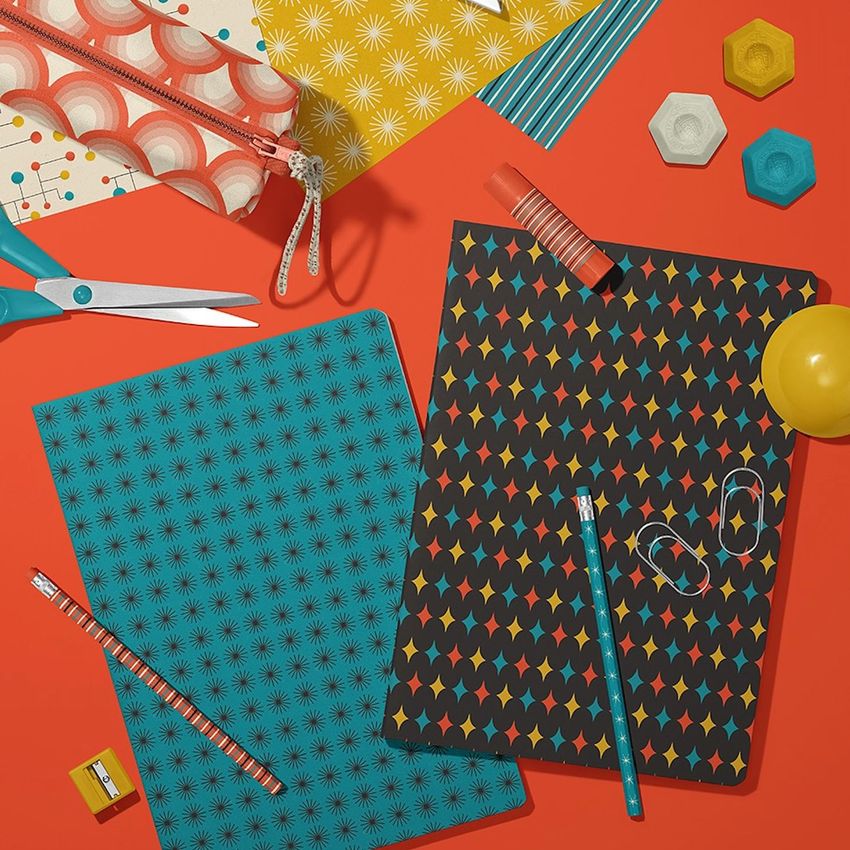 Stationery mockup featuring two classic A4 notebooks with geometric patterned covers on an orange surface, surrounded by office supplies.