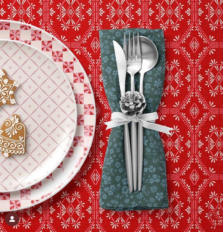 Plate, napkin, and tablecloth mockup showing a festive table setting with a red patterned tablecloth and decorative gingerbread cookies.