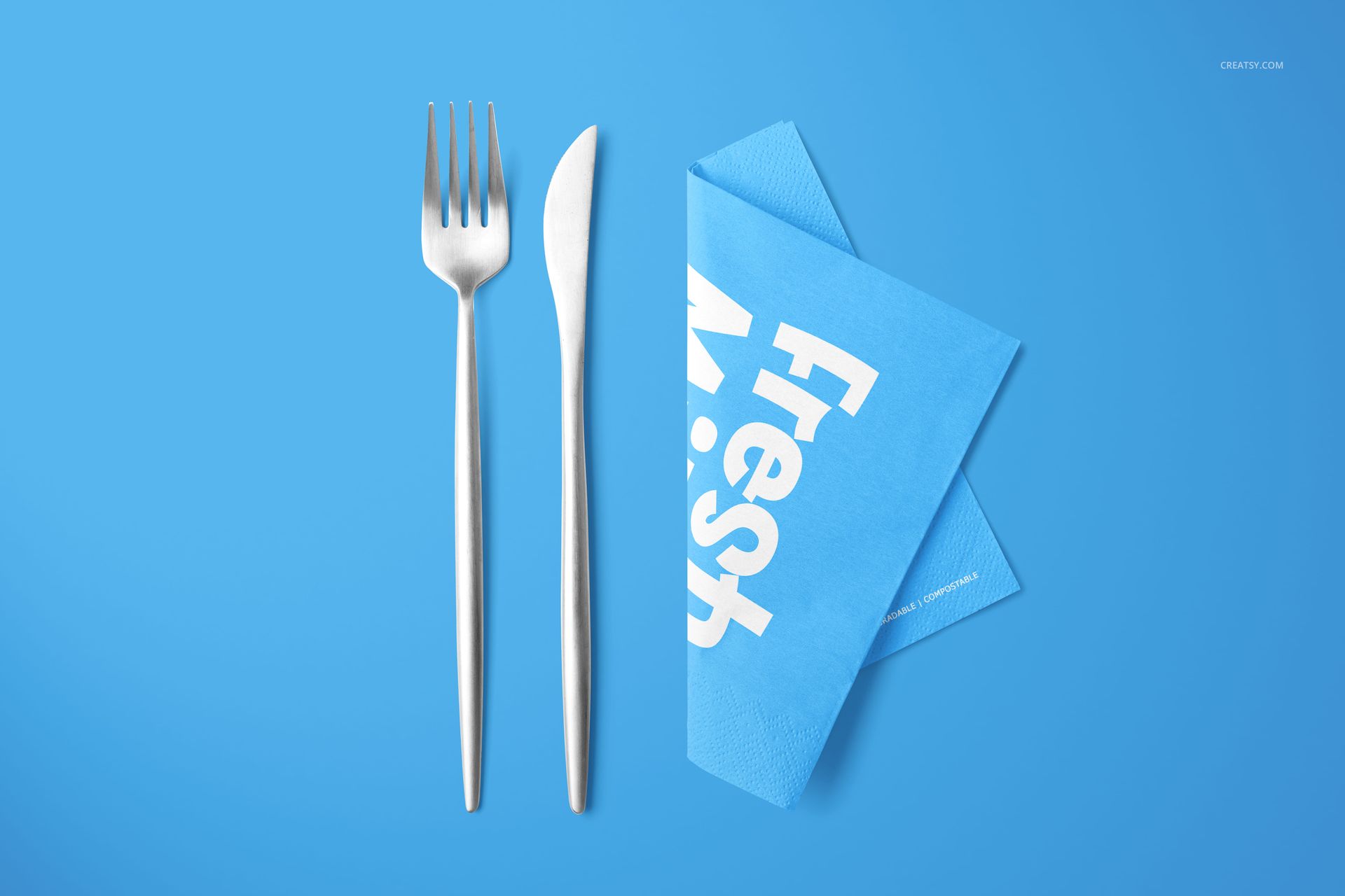 Blue napkin mockup set featuring folded napkins with white text, displayed next to silver fork and knife on blue surface.