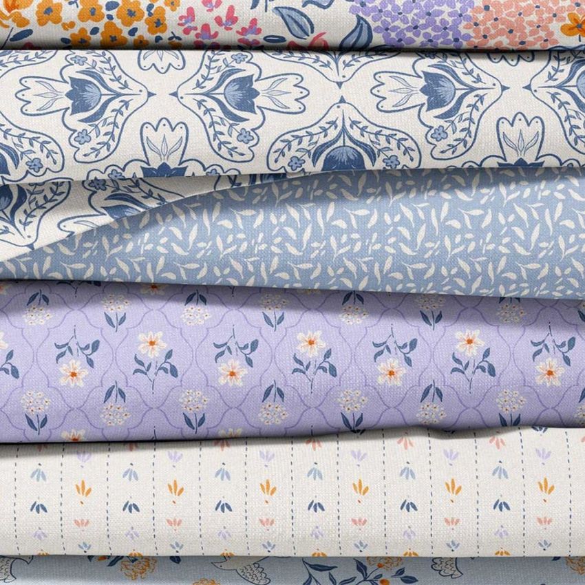 Fabric stack mockup showing five folded textiles with floral and botanical patterns in blue, lavender, and cream tones.