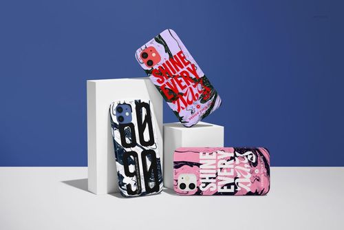 PSD mockup showing three iPhone 12 cases in assorted colors and graphic prints, positioned upright on minimalist white props.