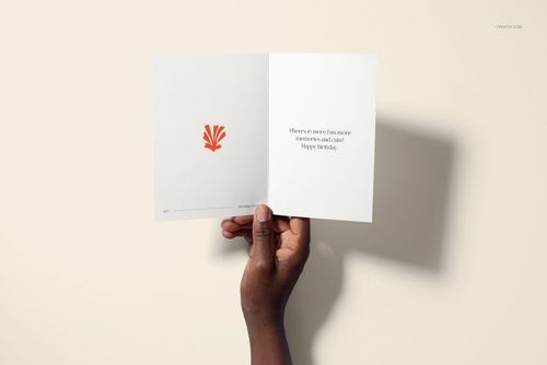 Open greeting card mockup with white interior, orange abstract illustration, and birthday message held by a hand.