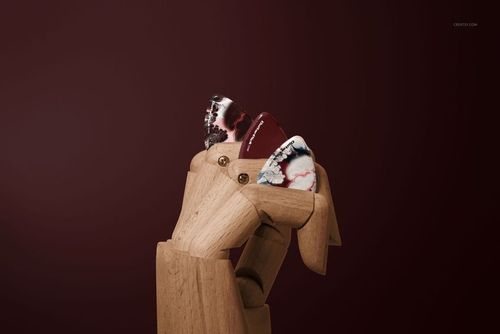 PSD mockup featuring a wooden hand displaying three multi-colored guitar picks, set before a solid burgundy background.