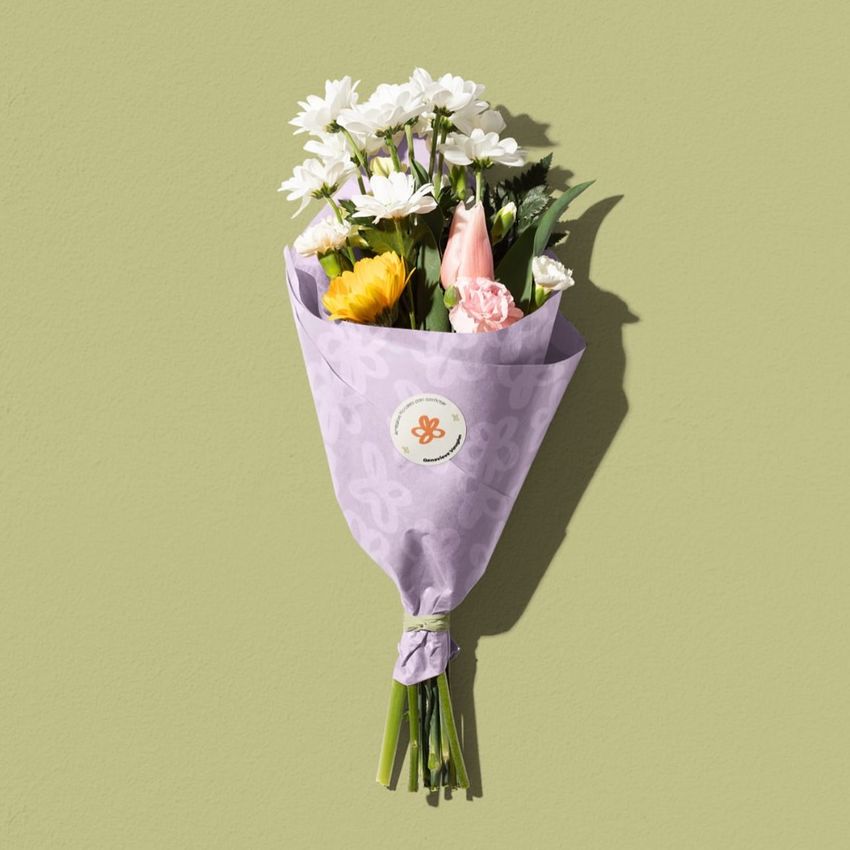 Flower packaging mockup featuring a bouquet wrapped in light purple paper with a subtle pattern, set against a pale green background.