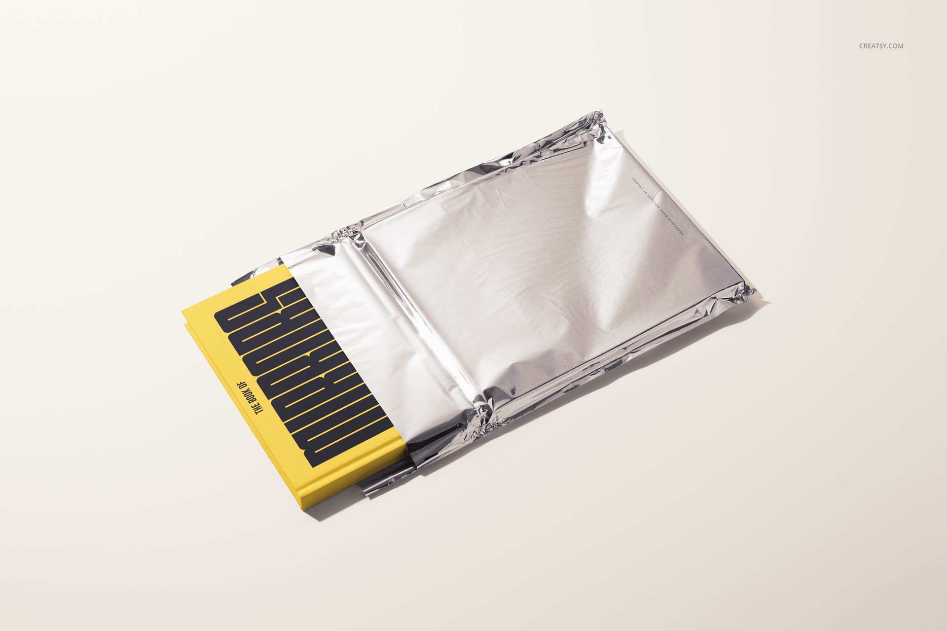 Front view of a hardcover book mockup with a bright yellow cover and black design, half inside a silver sleeve.