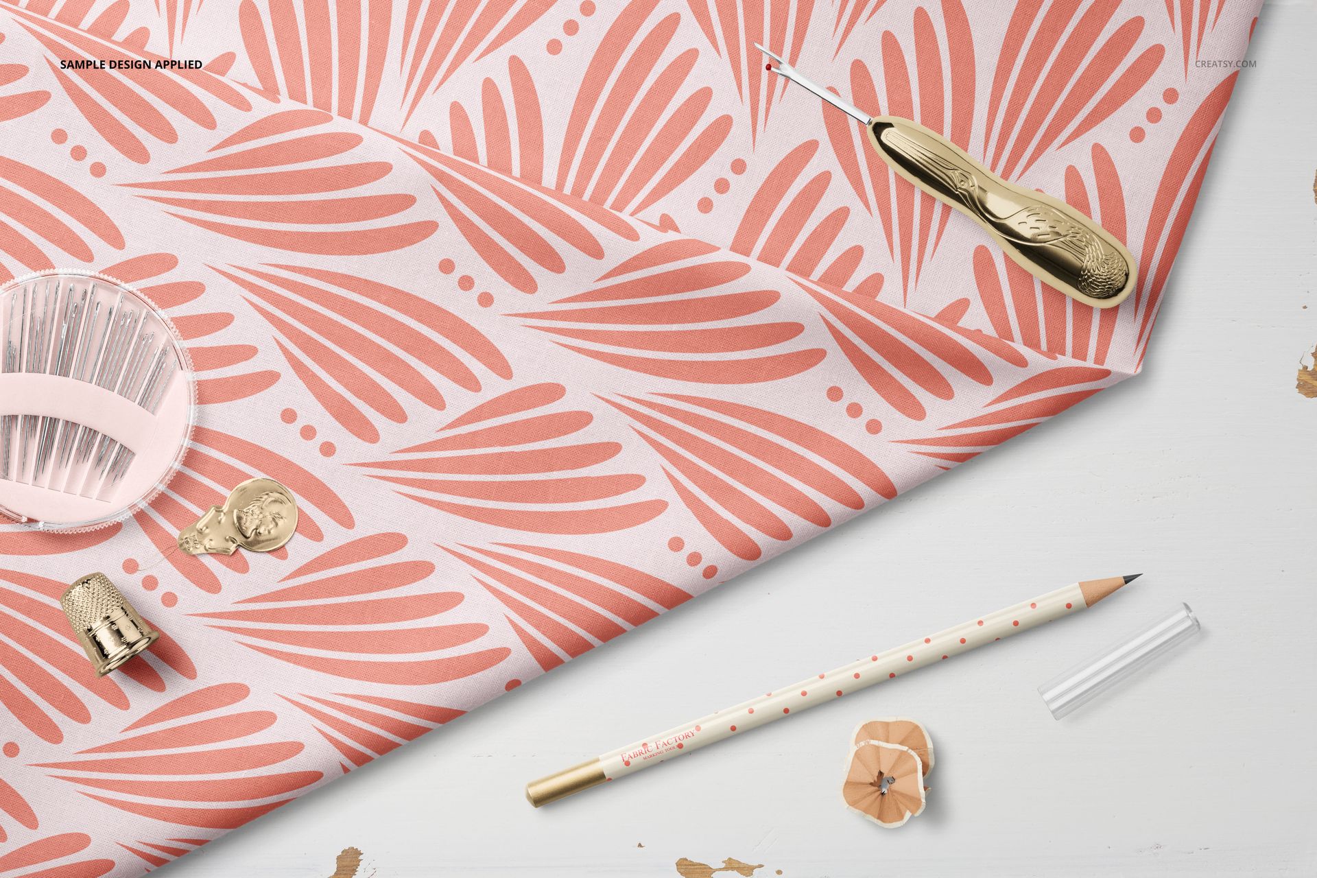 Top view of cotton fabric mockup featuring a coral leaf design, accompanied by a seam ripper, pencil, and thimble.