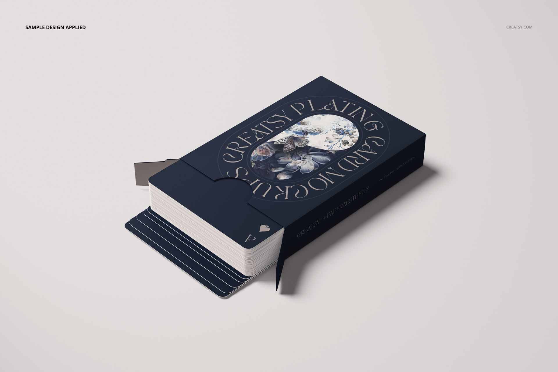 Front view of a playing cards mockup with a navy blue box, floral design, and partially open packaging on a light surface.