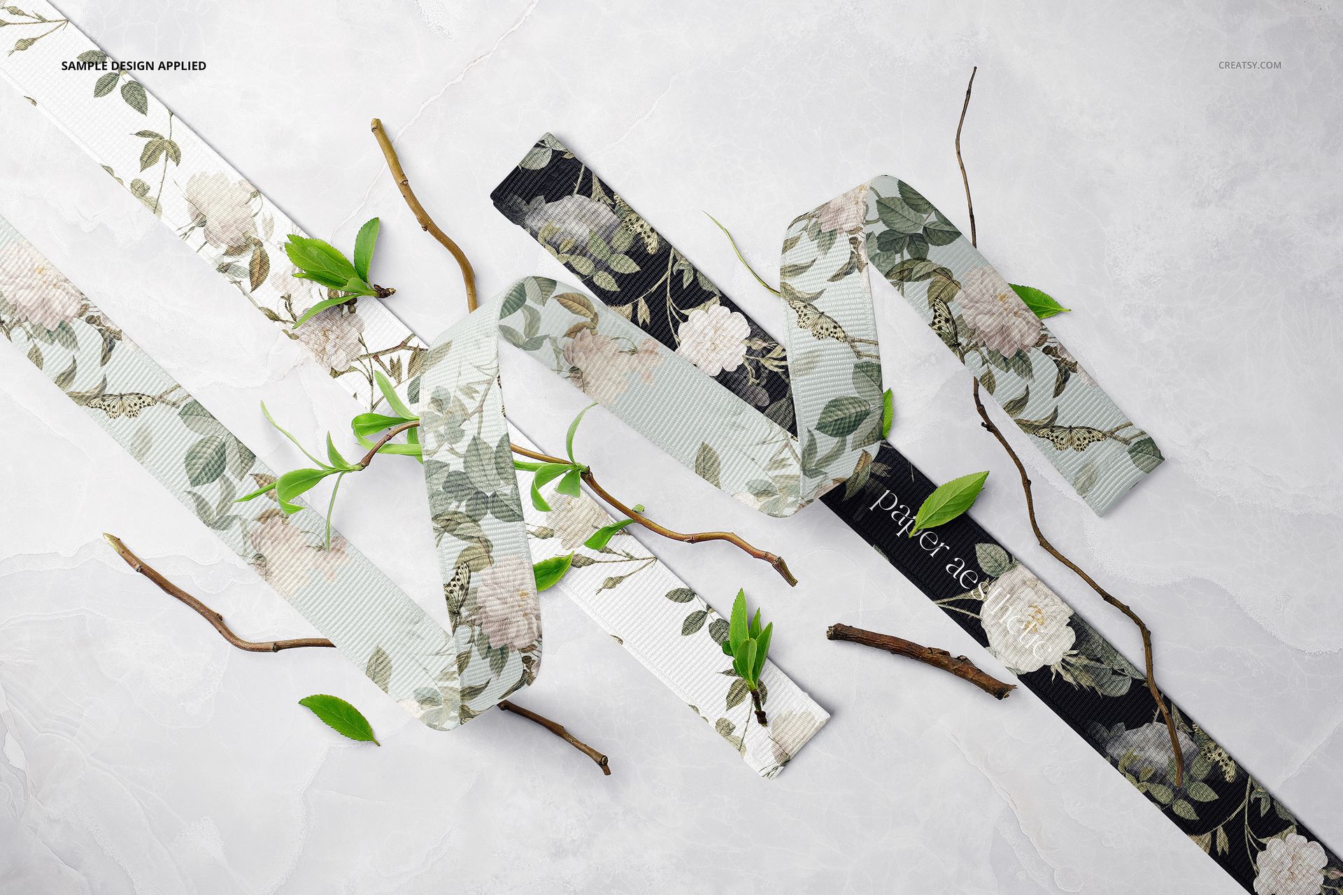 PSD mockup featuring assorted grosgrain ribbons with botanical prints, surrounded by twigs and green foliage from above.