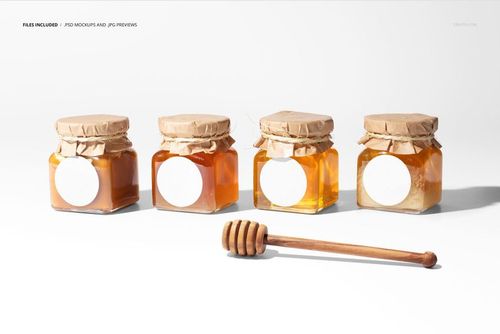 PSD mockup showing four glass honey jars with empty labels, kraft lids, and a honey dipper on a bright white background.