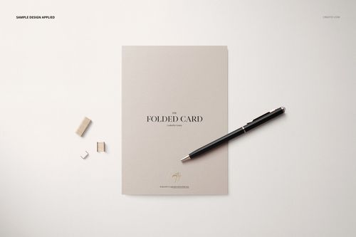 Folded card mockup displayed on a light surface with a black pen and small wooden blocks beside the card.