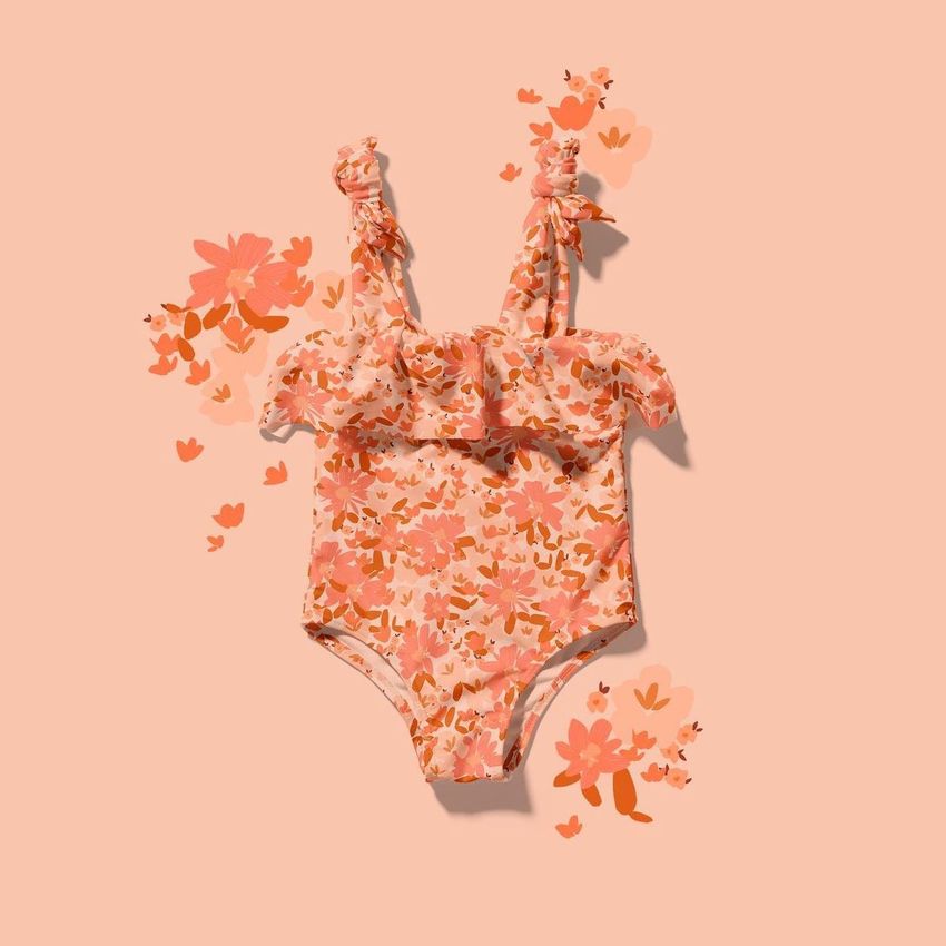 Baby swimsuit mockup featuring a ruffled one-piece with a pink and orange floral pattern on a matching peach background.
