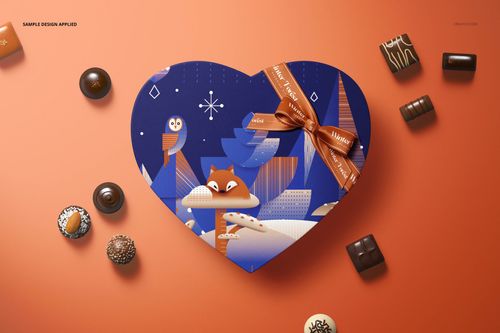 Heart-shaped chocolate box mockup with blue lid featuring fox and owl illustration, orange ribbon, and assorted chocolates on orange background.