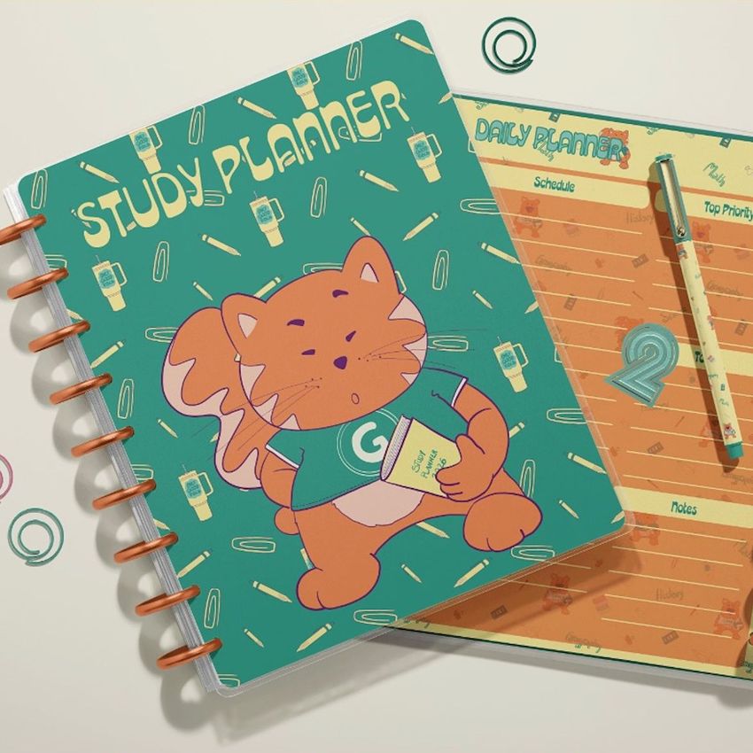 Top view of two spiral planners on a light surface, one with a cartoon cat illustration and the other with a lined daily planner layout.