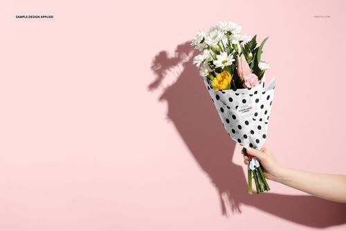 PSD mockup showing a floral arrangement in spotted wrapping paper, with a visible shadow on a pastel pink surface.