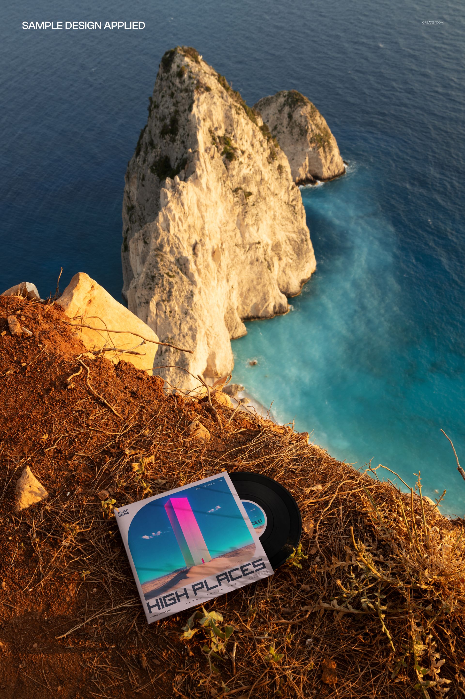 PSD mockup showing a vinyl record and square album sleeve on brown rocky terrain overlooking the sea.