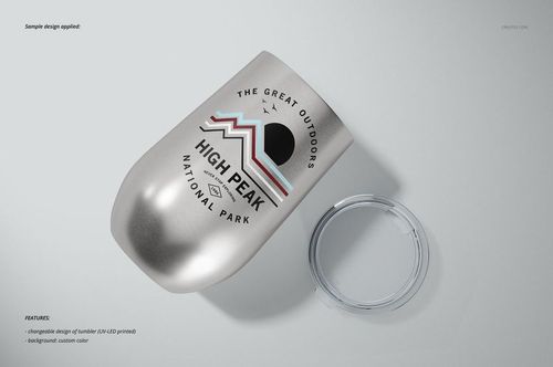 Stemless wine cup mockup featuring a metallic finish, geometric mountain design, and removable clear lid on a gray surface.