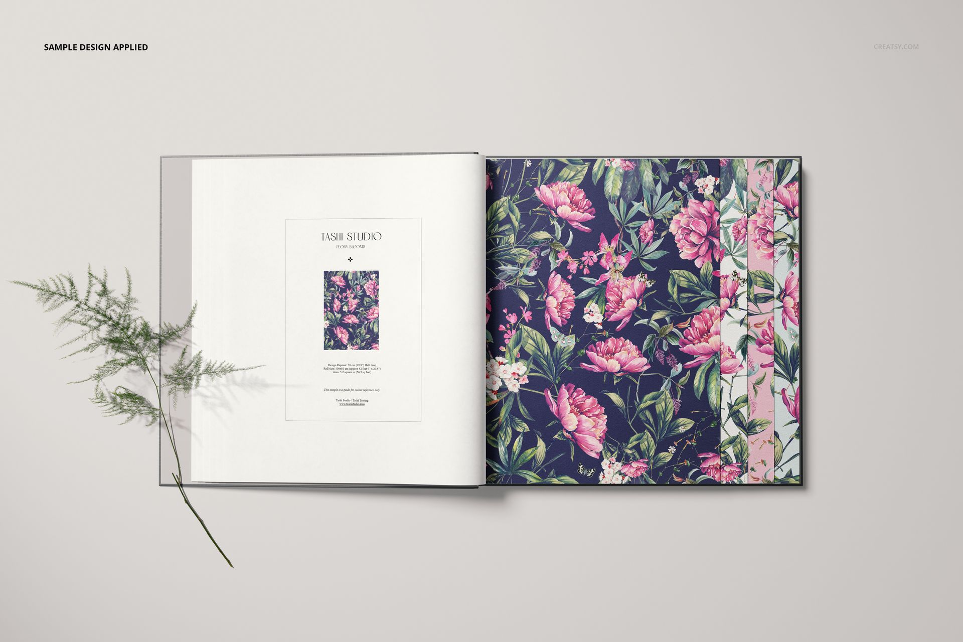 Top view of a wallpaper sample book mockup with vibrant pink floral design and green leaves on a navy page.
