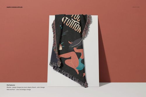 Jacquard fringed woven throw blanket mockup draped over a white board, featuring a dark abstract design.