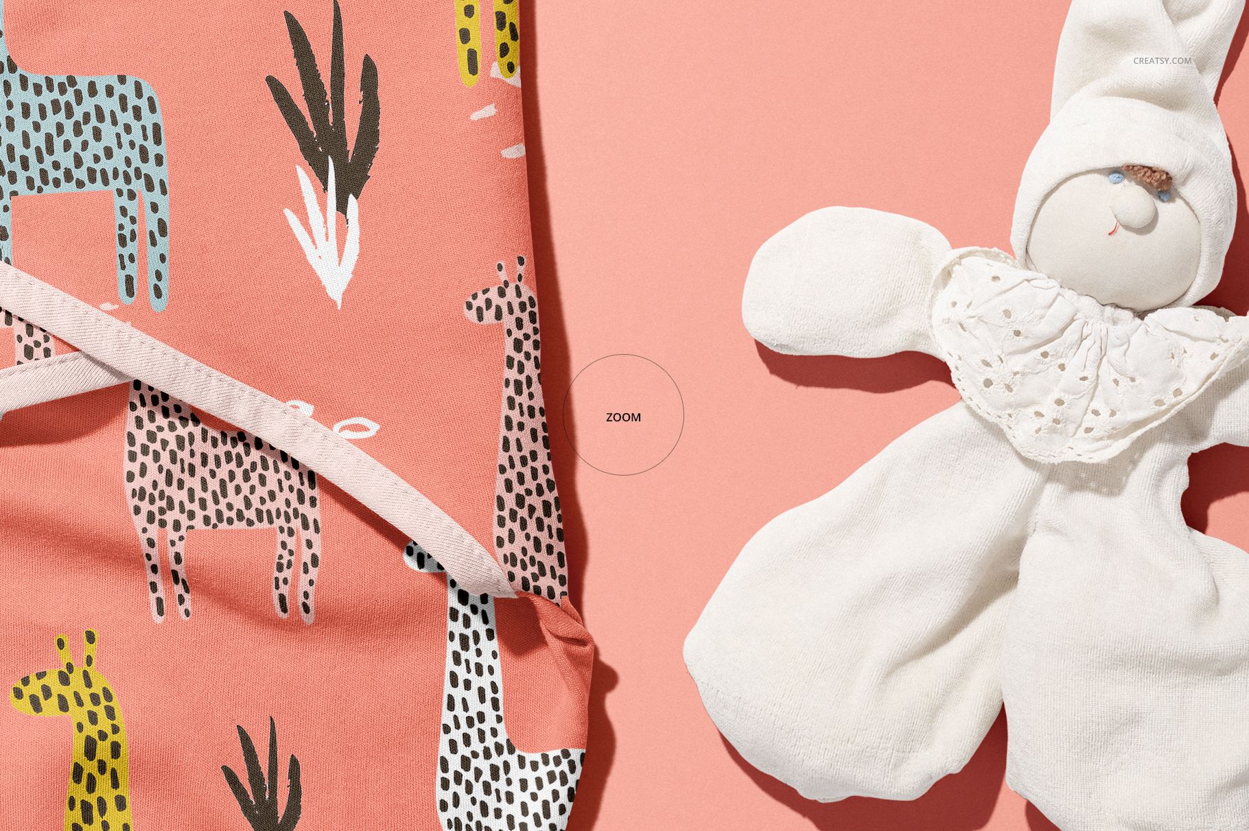 PSD mockup showing a patterned baby swaddle wrap and a plush doll arranged on a solid coral surface.