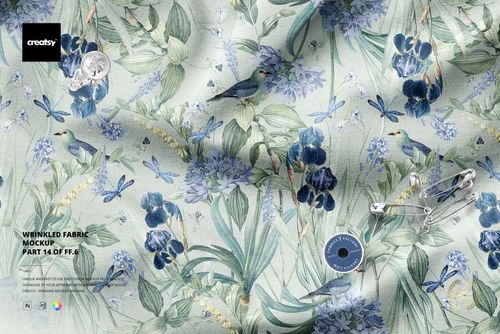 Top view of a wrinkled textile mockup featuring blue flowers, birds, dragonflies, and scattered sewing accessories.