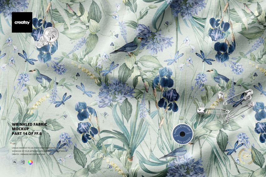 Top view of a wrinkled textile mockup featuring blue flowers, birds, dragonflies, and scattered sewing accessories.