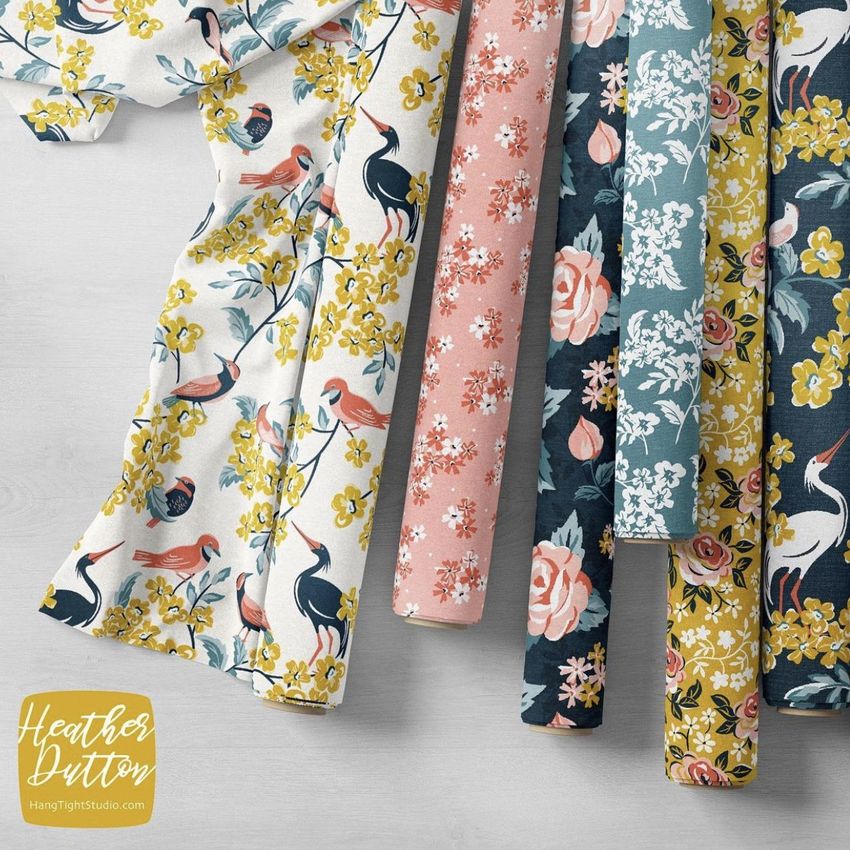 Fabric rolls mockup showing six patterned fabric rolls with floral and bird designs in yellow, pink, blue, and white tones.