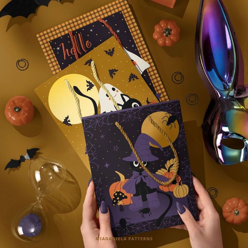 Halloween paper gift bag mockup featuring a purple bag with witch-themed illustrations, surrounded by pumpkins, bats, and festive cards.