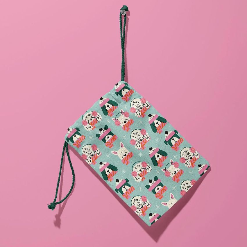 Hanging drawstring pouch mockup featuring a playful dog and animal pattern on a light green fabric, set against a pink background.