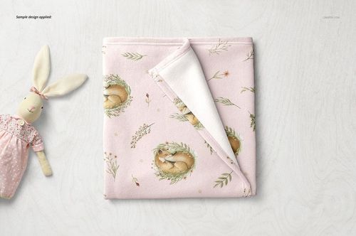Top view of a square baby blanket mockup with gentle animal and floral patterns, next to a plush bunny toy.