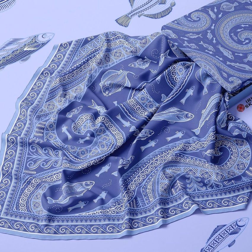 Twill silk scarf mockup featuring a blue scarf with intricate fish and paisley patterns, displayed on a flat surface with paper fish cutouts.