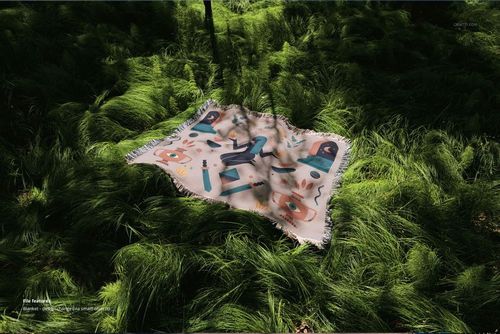 Fringed jacquard throw blanket mockup featuring a vibrant pattern, displayed on lush grass under dappled sunlight.
